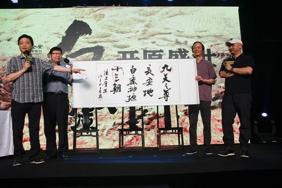《白鹿原》导演王全安（右一）与发布会主持人崔永元（左一）现场展示著名书法家任平（右二）创作的书法作品。