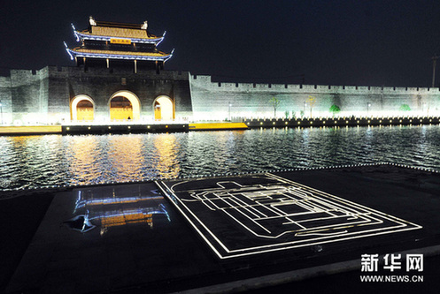 2月2日晚，苏州火车站南广场前的大型浮雕石碑刻《平江图》亮灯后与环古城河对岸的平门城墙段相映成景。新华网图片 杭兴微 摄