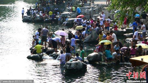 8月12日，汹涌的游客队伍向泉水景区和护城河涌来，泉水浴场爆满成了“饺子锅”，市民需要等候一个多小时才能入场；而护城河边可以纳凉的地方都被“占领”，成了“泡脚池”。图片来源：CFP视觉中国