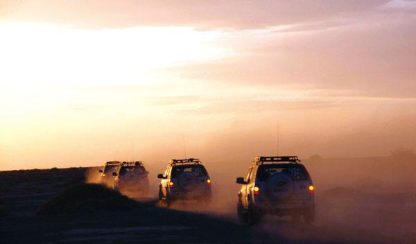 甘肃瓜州，夕阳下行驶在戈壁滩上的车队。