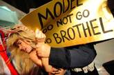 当地时间2012年2月24日，意大利米兰，米兰2012秋冬时装周，Versace秀场外被一群激进的女权主义组织所包围。情绪激动的女组员们纷纷真空上围大露点，高举着“模特们别进妓院”的招牌大闹Versace秀场。旋即引来警察的暴力管制。场面相当混乱。