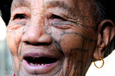 在海南省保亭黎族苗族自治县一景区拍摄的黎族阿婆，其刺于面颊两侧的颊纹清晰可见。文身是黎族传统习俗，文身的部位多，文饰复杂且图案变化多样，仅面纹就有37式。黎族的文身习俗历史悠久，至今已保存了三千多年，自汉代开始，便有文字记载。文身，黎语叫做“打登”，亦叫“模欧”。
