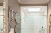 狭长的卫浴设计，同样将淋浴房设计在空间尽头，玻璃门当隔断，保证淋浴房的独立感。前方的设计也遵循一般规律，功能区都设计在一侧墙面上，另一侧则用来放置装饰物或者小挂钩。