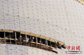 2014年1月5日，北京，工人在为人民日报新大楼的外层安装白色的琉璃棍。（实习编辑：容少晖）