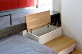 设计师在空间的一侧建造了一个小平台，将厨房与浴室安置其上，而平台下的空间就刚好可以用作收纳，住户可以将睡床在白天完全嵌入其中隐藏起来，也可以留出一部分变成沙发。除此外，这里也还有一个小吧台、工作台，以及充足的木质收纳柜。（实习编辑：刘宁馨）