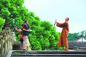 　　7月5日，一名僧人在普陀山法雨寺景区为游客拍照。 CFP 图
