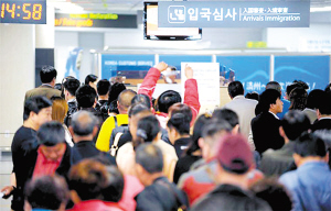 　　(资料照片)：在韩国济州国际机场二层的审查台前，等待接受入境审查的中国乘客排起了长队。
