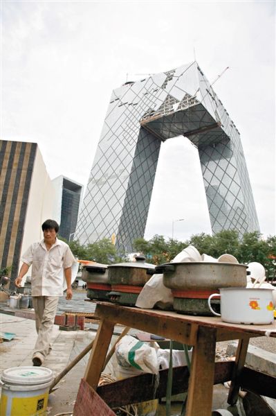 2008年7月5日，央视新大楼下的农民工的临时住所与饭碗，与城市元素形成对比。图/CFP