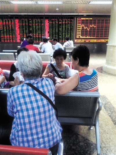 7月2日,东直门一证券交易厅内股民午间休市时在打牌。