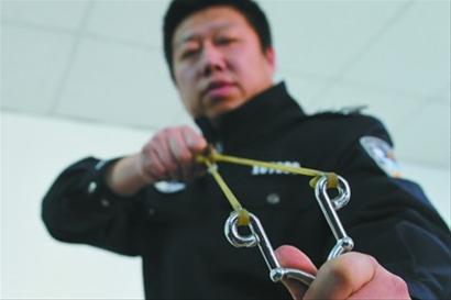 沈阳市公安局和平分局沈水湾派出所民警演示嫌疑人的作案工具——弹弓。