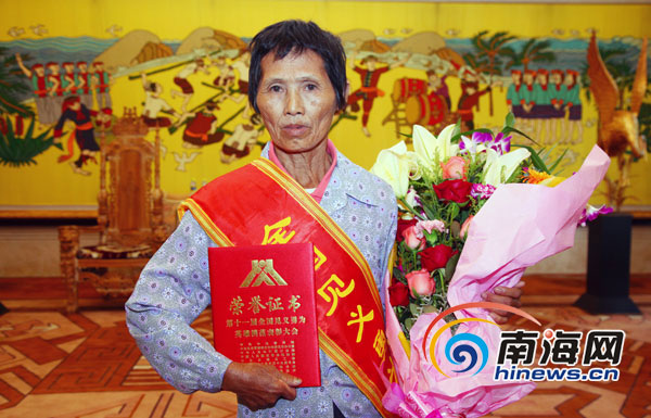 黄明的母亲手捧她儿子的“全国见义勇为模范”荣誉称号证书(南海网记者张茂摄)