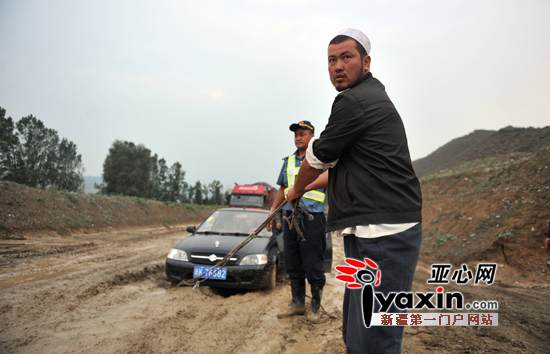 216国道上，一名从吐鲁番过来的游客因为车子被陷自救失败后等待大车救援。亚心网记者 赵宇飞 摄
