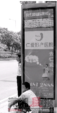 7月11日下午，长沙公交西二环沿线站台缺少遮阳棚，烈日下乘客们只能蹲在站牌的阴影里。图/实习生宋汉涛 记者华剑