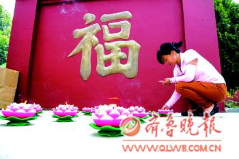一位村民在庙内摆上莲花形的蜡烛祈福。
