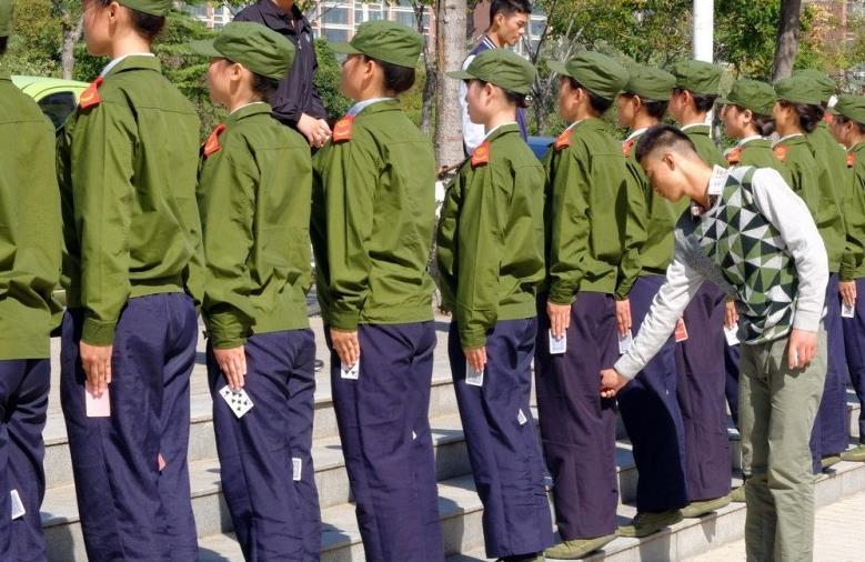 在郑州某大学校园内,数十名大一女生一字排开前脚掌站在台阶上站军姿