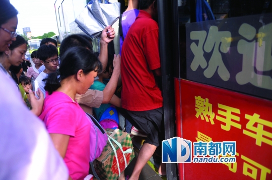 7月17日下午,在中山汽车总站公交站,乘客蜂拥挤上202路公交车.