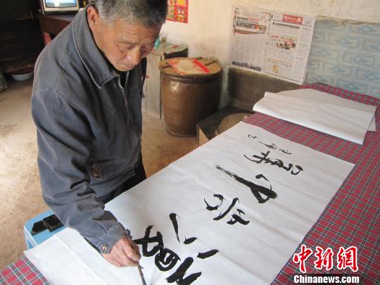 图为李春晖在炕上写书法的情形. 李忠勇 摄