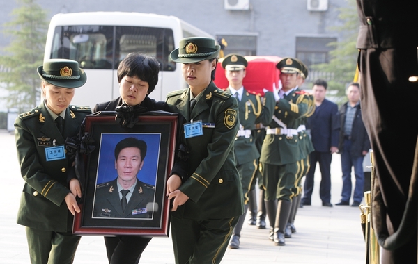 烈士刘洪坤的妻子抱着他的遗像悲痛欲绝,身后就是丈夫的灵柩.