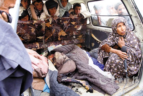11日,一名阿富汗妇女坐在被美军士兵枪杀的儿童尸体旁接受采访
