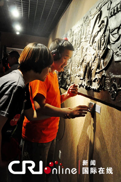 触摸博物馆中,盲人朋友戴着可以自动进行语音讲解的耳机,触摸世界