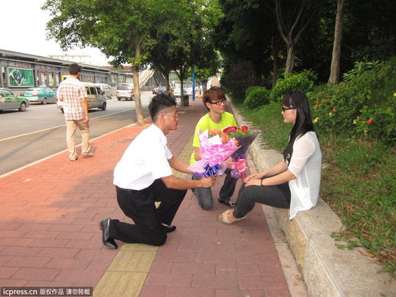 两名看上去二十多岁男子各拿一束玫瑰花,当众单膝下跪向一名女生